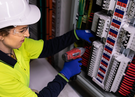 Electrical worker in safety gear working on a circuit panel