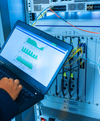 Technician providing preventive maintenance services using a laptop to connect to an electrical system