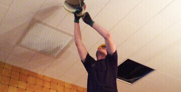 A Gibson Electric worker fixing a light in the ceiling