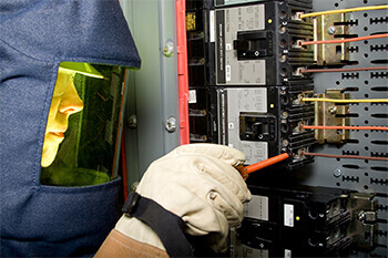 Technician wearing a safety mask assessing electrical equipment